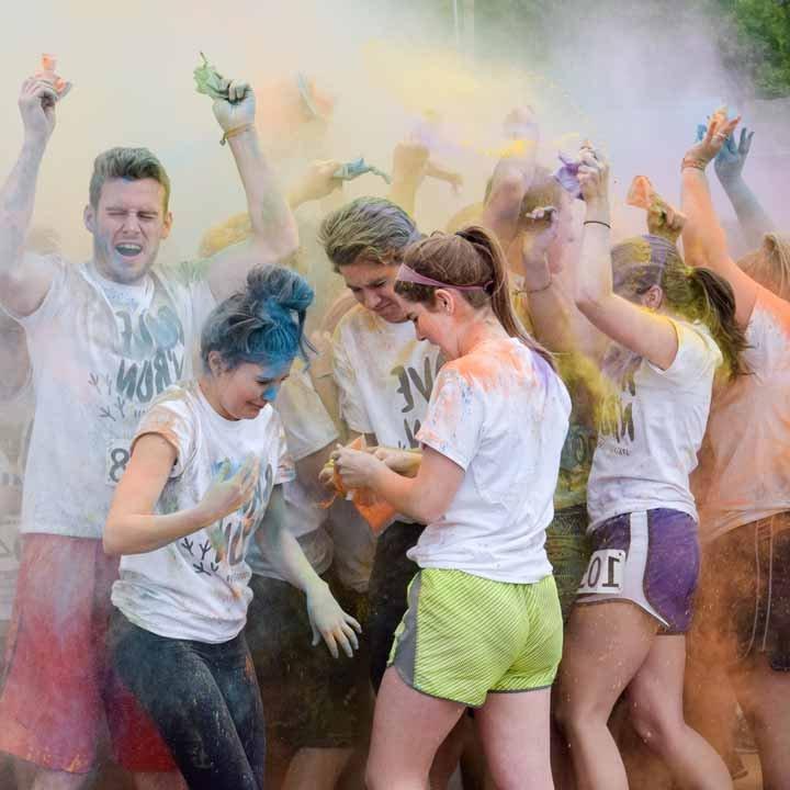 学生s having fun in a cloud of brightly-colored powder at the Color Run